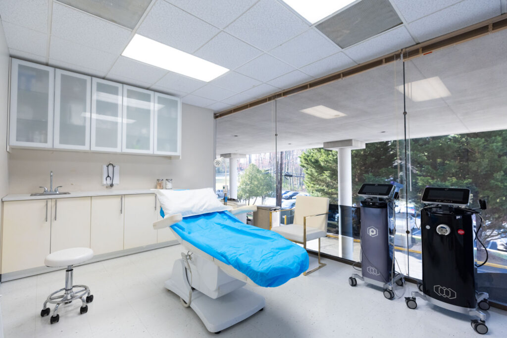 A consultation room with a bed in the middle for a patient to discuss treatment for saggy boobs near Rockville.