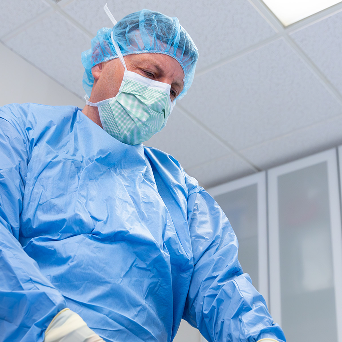 Dr. Faulkner looks down at a patient as he removes a cancerous lesion during basal cell skin cancer surgery near Bethesda, MD.